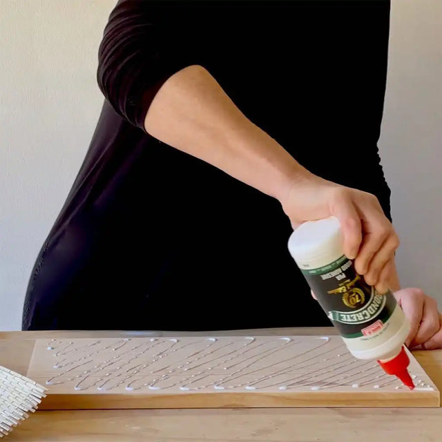 Person applying glue to a wooden surface with a glue gun.