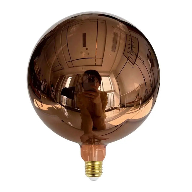 Large reflective copper-colored light bulb on a white background