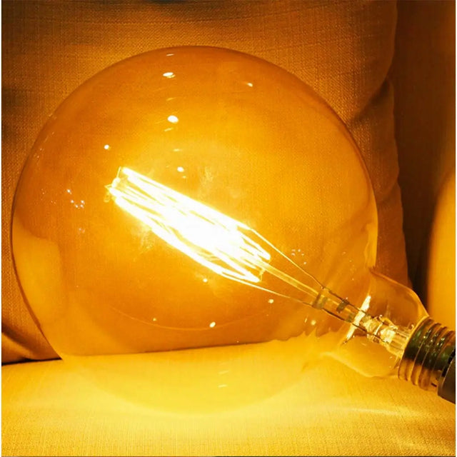 Vintage-style light bulb emitting a warm glow on a soft fabric background