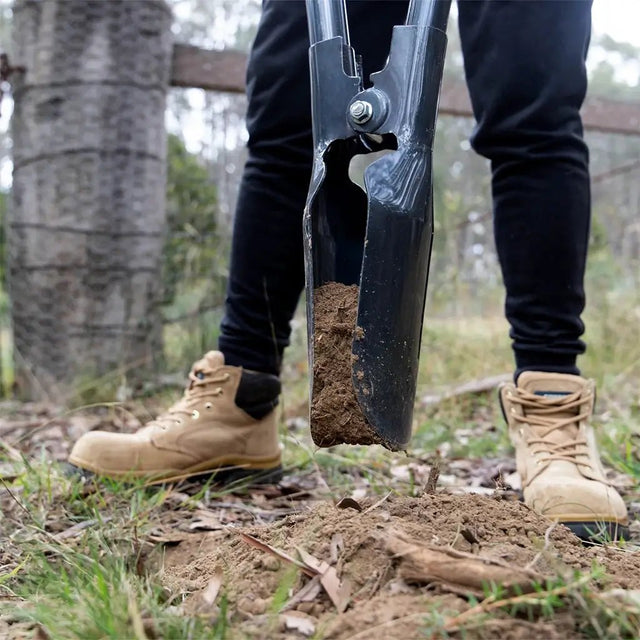 Person using a garden hole pincer in a natural setting with feet wearing beige boots.