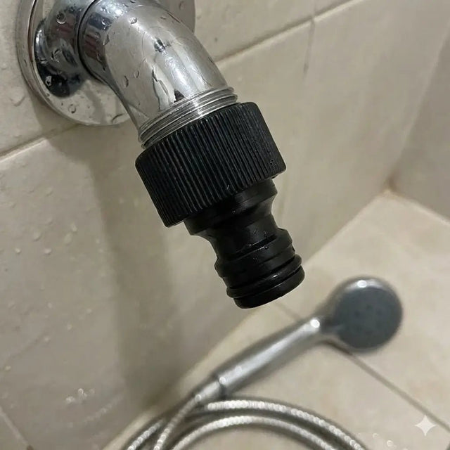 Black garden hose nozzle attached to a shower head on a tiled wall.