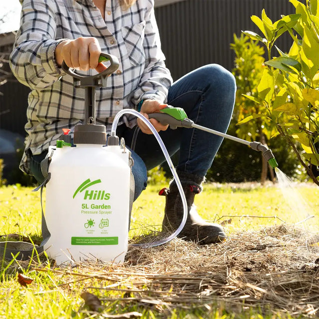 Person using a Hills brand garden sprayer on plants outdoors