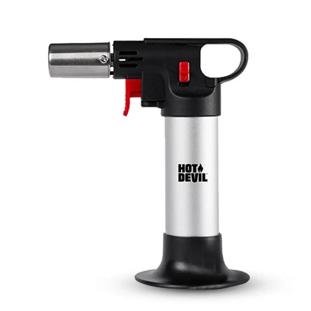 A torch lighter with a silver metallic body, black plastic head and base, and red accents on the trigger and switch, featuring the HOT+DEVIL logo printed on the silver body, set against a plain white background.