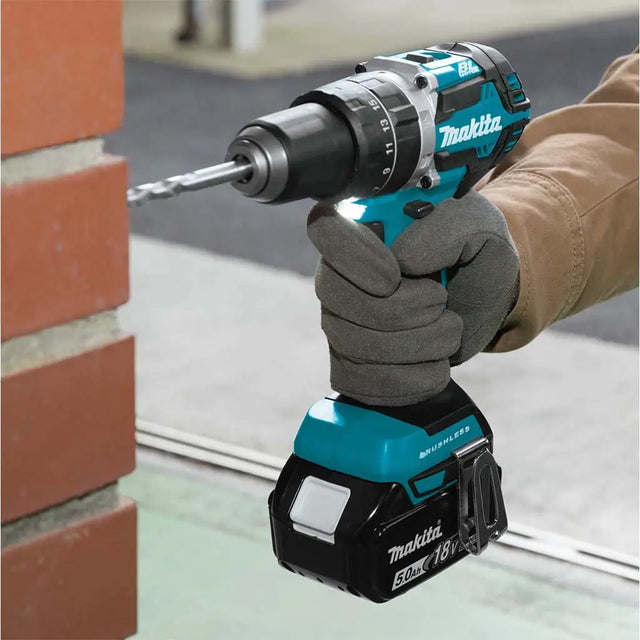 Person using a Makita cordless drill on a brick wall