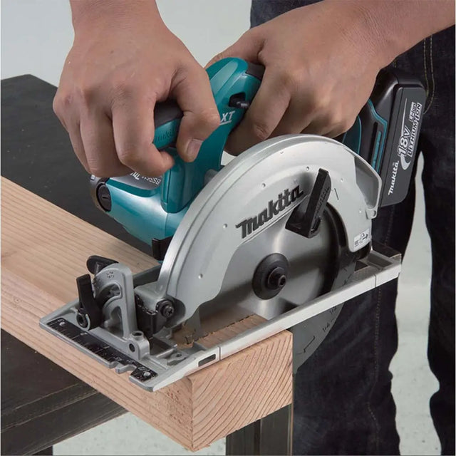Person using a Makita circular saw on a wooden board