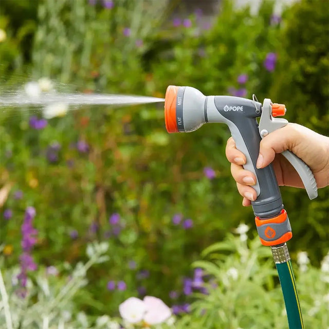 Person using a hose with a spray nozzle in a garden setting