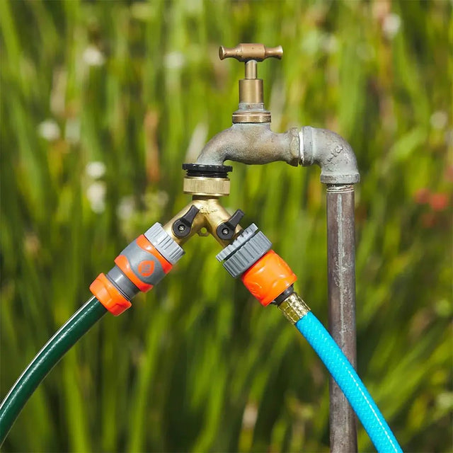 Garden faucet with hoses attached against a green background