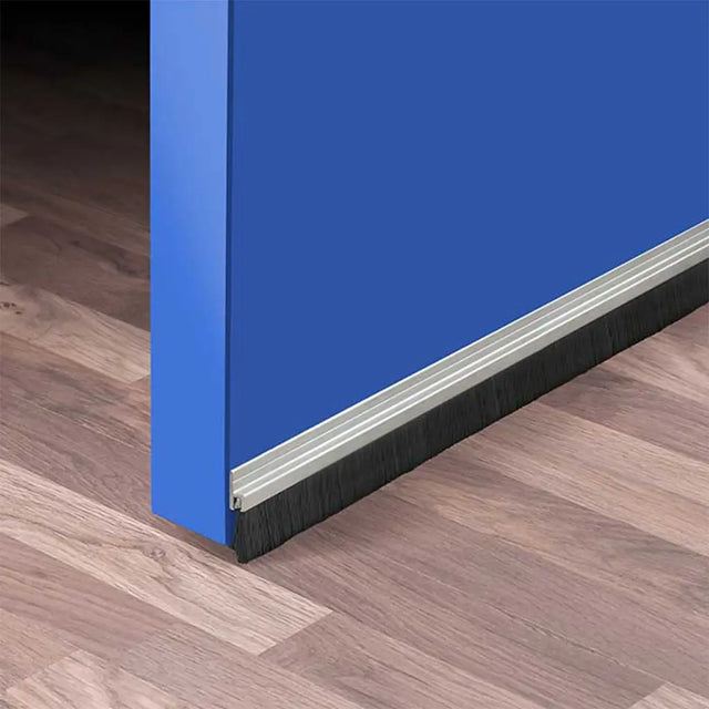 Close-up of a blue door with a threshold ramp on a wooden floor