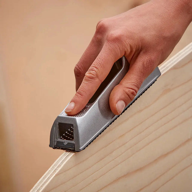Hand using a small tool on a wooden surface