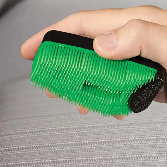 Green brush with black handle held by a hand on a gray surface