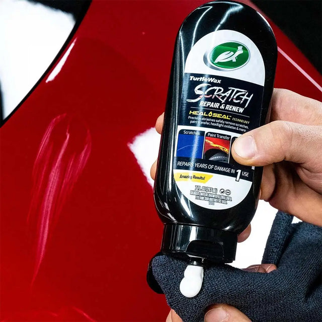 Person holding a bottle of Turtle Wax Scratch Repair & Renew product with a car scratch in the background.