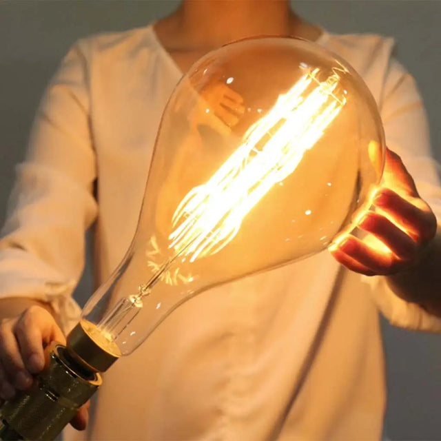 Person holding a large, clear light bulb with a warm glow.