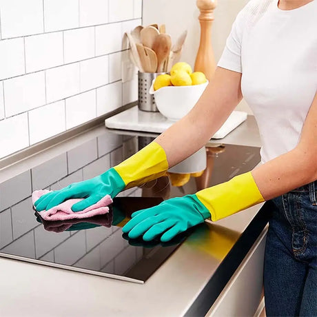 Person cleaning a stove top with gloves on in a kitchen setting