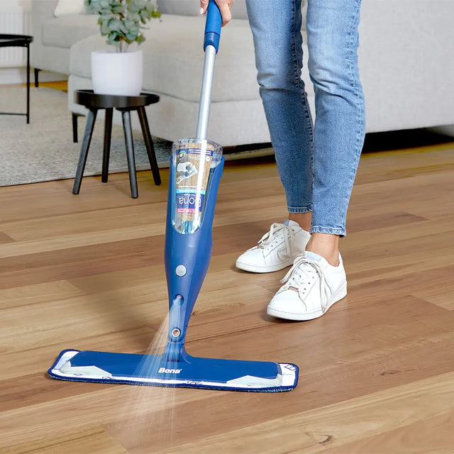 Person using a Bona floor cleaning system on a wooden floor in a living room.