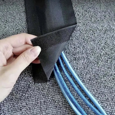 Hand holding black mesh over blue cable on gray carpet