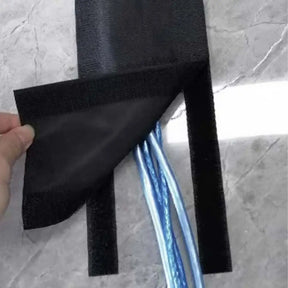 Black adhesive strip being applied to a textured gray surface with a blue cable underneath.