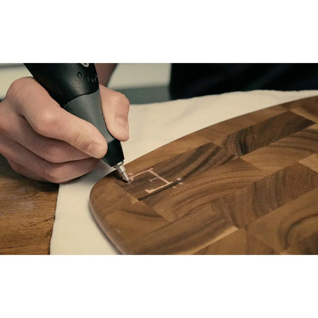 Person using a wood burning tool to engrave a design on a wooden surface.