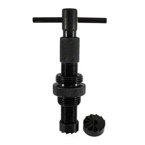 A black metal threaded tool with a T-handle on top and a separate small circular component placed beside it, shown on a plain white background.