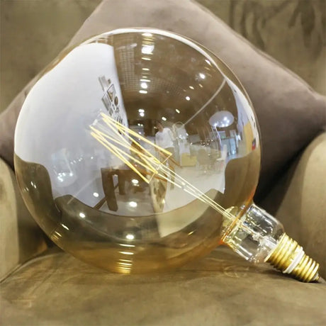 Clear glass light bulb with visible filaments on a textured surface