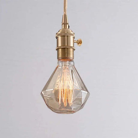 Vintage-style pendant light with a clear glass shade and brass fixture on a gray background