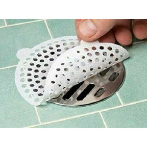 Hand placing a perforated white plastic drain cover over a metal drain.