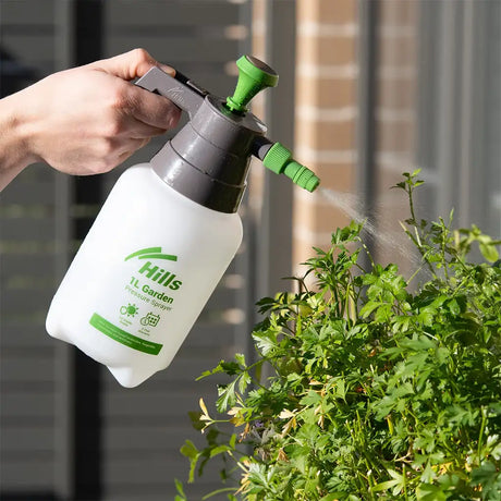 Person using a Hills 1L Garden spray bottle to water plants outdoors.