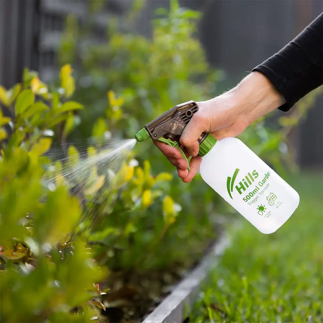 Person using a Hills branded spray bottle to water plants outdoors