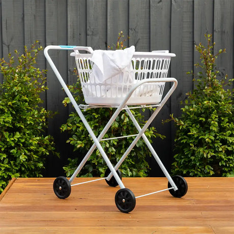White folding cart with a laundry basket on a wooden surface outdoors.