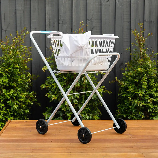 White folding cart with a laundry basket on a wooden surface outdoors.