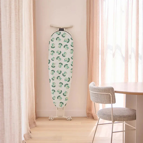 Patterned ironing board against a light pink curtain backdrop