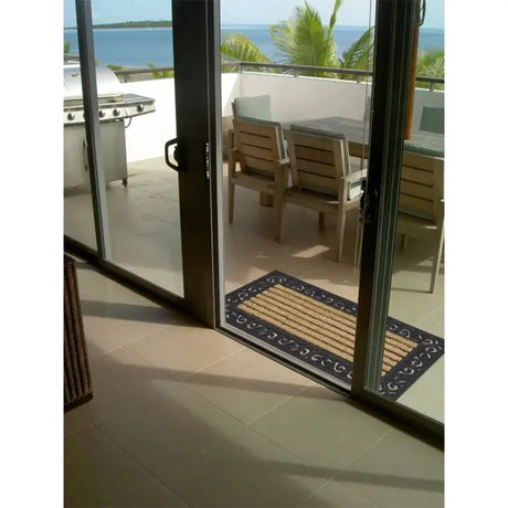 Open glass door leading to a patio with outdoor furniture and ocean view