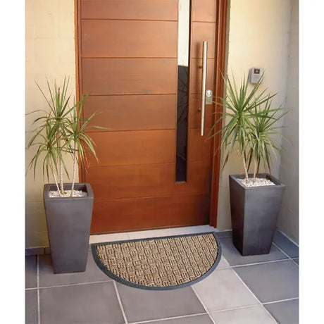 Modern wooden door with two potted plants and a doormat on a tiled floor.
