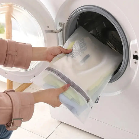 Person placing a mesh laundry bag into a washing machine