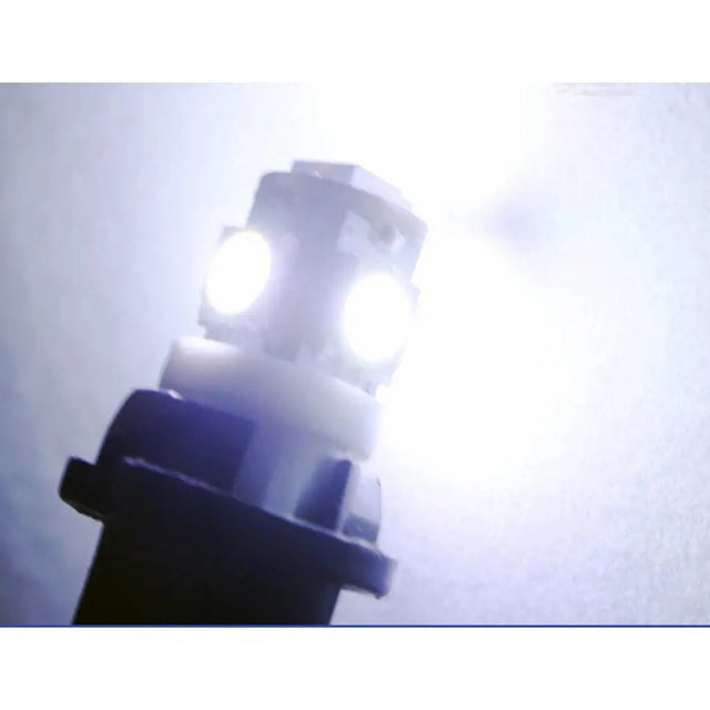 Close-up of a car headlight bulb with a white light on a blurred background