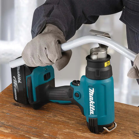 Person using a Makita power tool on a white background