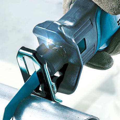 A close-up action shot of a teal and black reciprocating saw being used to cut a metal pipe, with a gloved hand holding the tool.