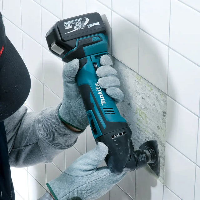 Person using a Makita power tool on a tiled wall