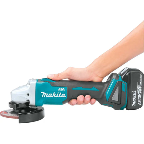 Makita angle grinder held by a hand on a white background