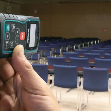 Hand holding a device in front of an empty room with blue chairs