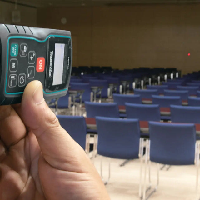 Hand holding a device in front of an empty room with blue chairs