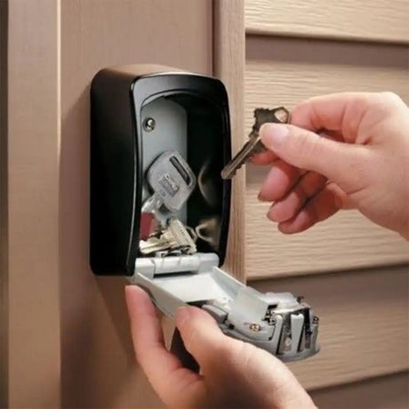 Person inserting keys into a key storage device mounted on a wall.
