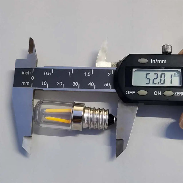 Digital caliper measuring a small LED light bulb against a white background