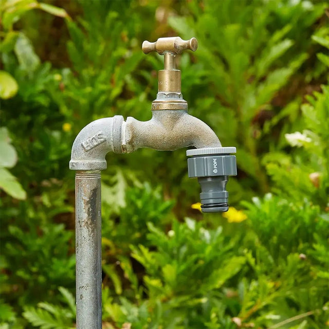 Rusticated outdoor faucet with green foliage in the background
