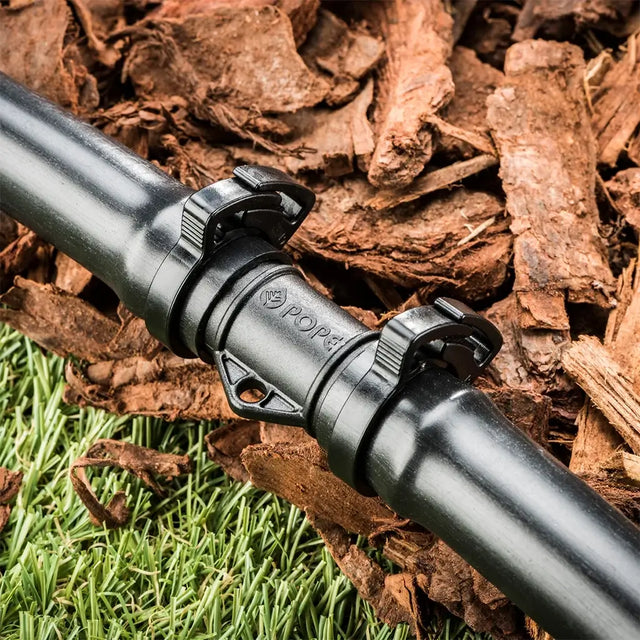 irrigation rod with a black clip on a background of brown mulch and green grass
