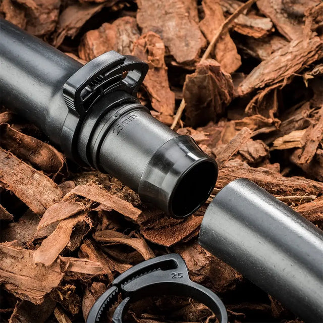 Black rifle scope on a bed of wood chips