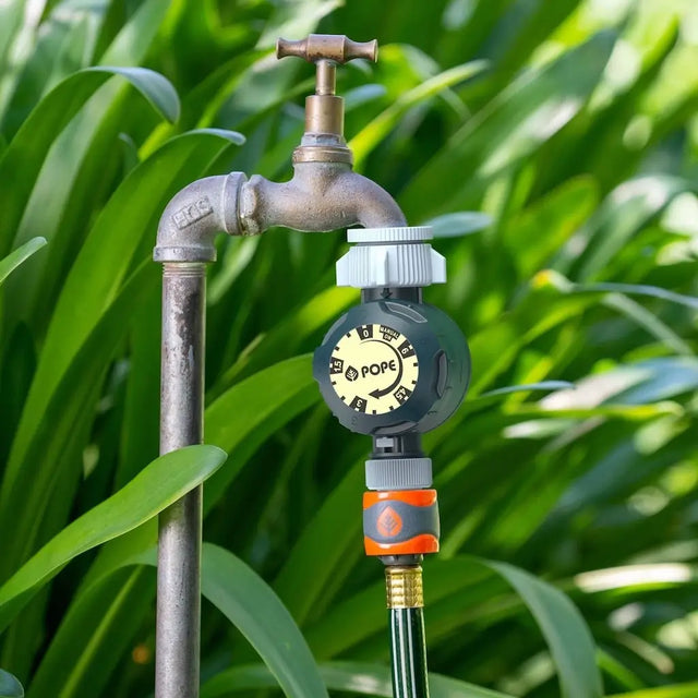 Garden faucet with pressure gauge on a green leafy background