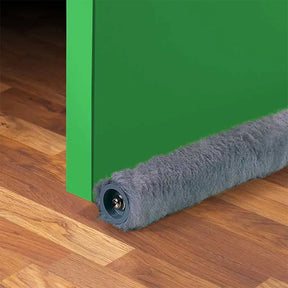 Gray carpeted door stopper on a wooden floor next to a green door