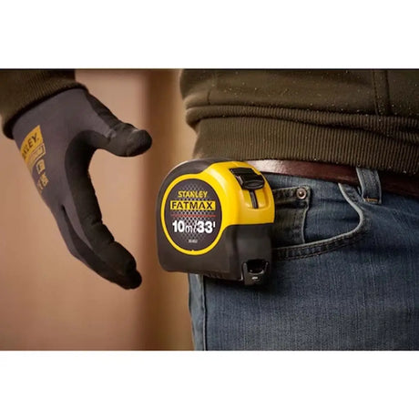 Person holding a Stanley FatMax tape measure with a blurred background