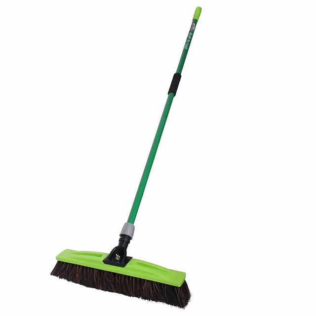 Green push broom with black bristles on a white background