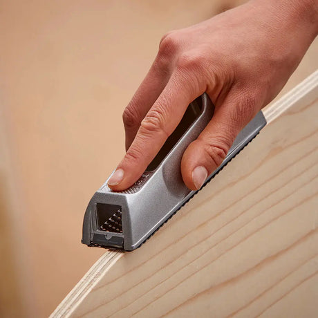 Hand using a small tool on a wooden surface